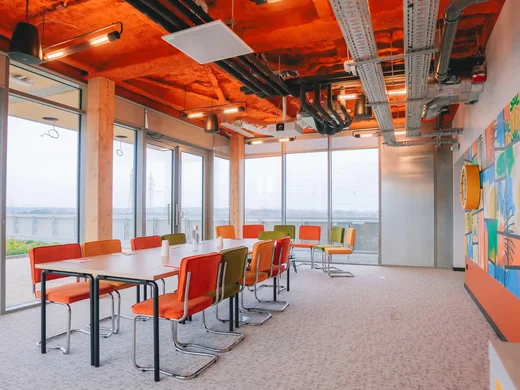 Salle de réunion lumineuse ouverte sur l’extérieur, mobilier coloré et fresque murale